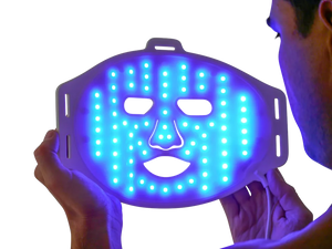 Man holding LED blue light therapy face mask for acne treatment and skin care