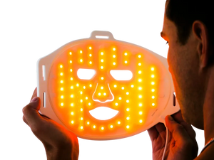 Man holding LED orange light therapy face mask for skin treatment and rejuvenation