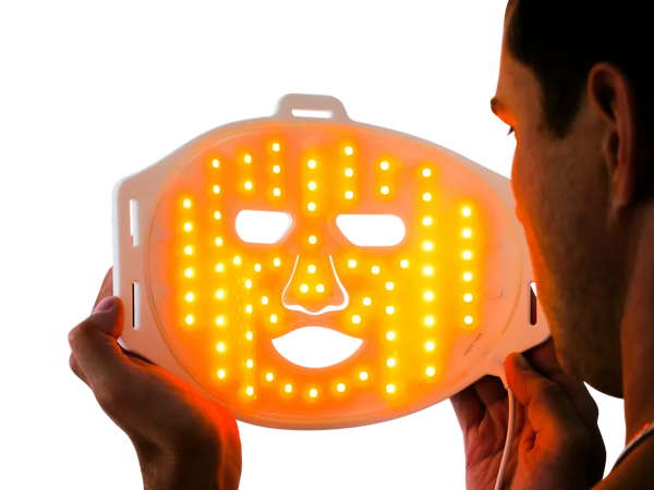 Man holding LED orange light therapy face mask for skin treatment and rejuvenation
