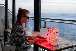 Woman using QuantumGlow portable red light therapy panel on her face